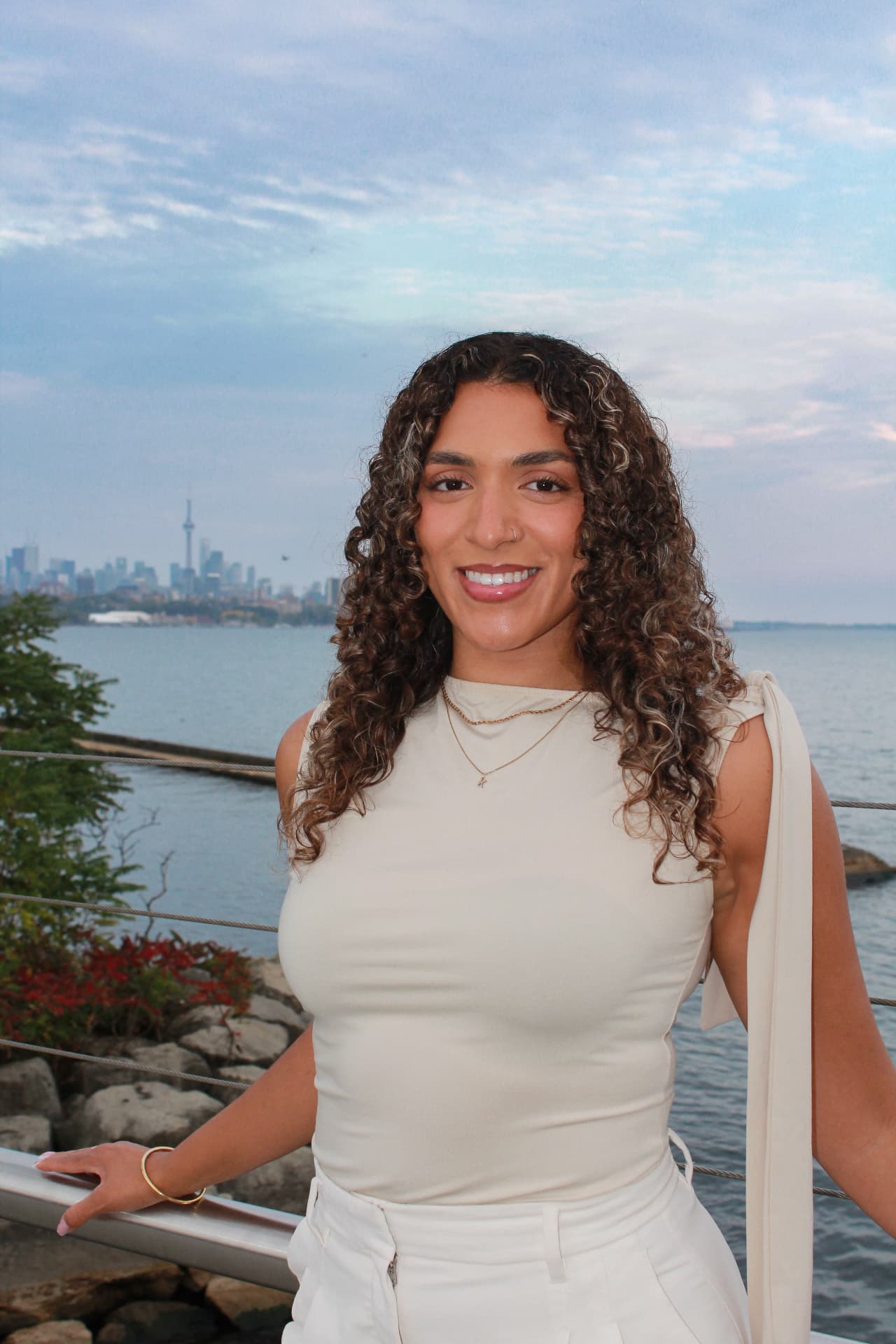 Kaysia Nedjelski standing at a waterfront railing, the Toronto skyline behind her